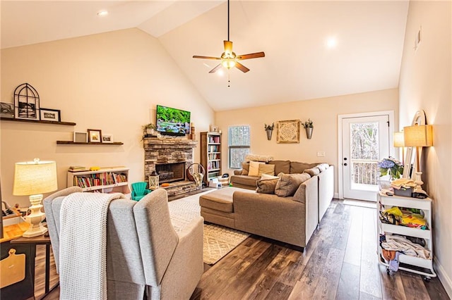 living area featuring ceiling fan, high vaulted ceiling, dark wood-type flooring, and a stone fireplace