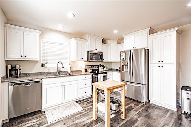 kitchen featuring appliances with stainless steel finishes, white cabinetry, a sink, and dark wood-style floors