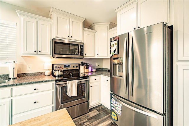 kitchen with appliances with stainless steel finishes, dark countertops, and white cabinetry