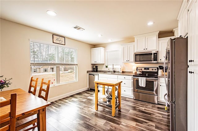 kitchen featuring dark wood-style floors, visible vents, appliances with stainless steel finishes, white cabinetry, and a sink