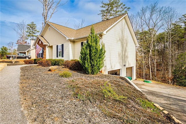 view of home's exterior featuring driveway and roof with shingles