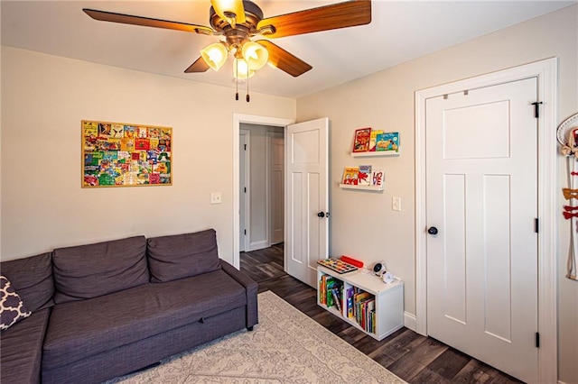 living area featuring dark wood-type flooring and a ceiling fan