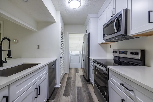 223 Tuxworth Cir, Decatur, GA 30033 - kitchen featuring appliances with stainless steel finishes, a sink, a textured ceiling, dark wood finished floors, and washer and clothes dryer