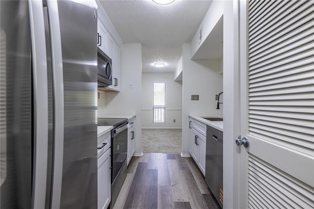 223 Tuxworth Cir, Decatur, GA 30033 - kitchen with a textured ceiling, a sink, light countertops, stainless steel appliances, and dark wood-type flooring