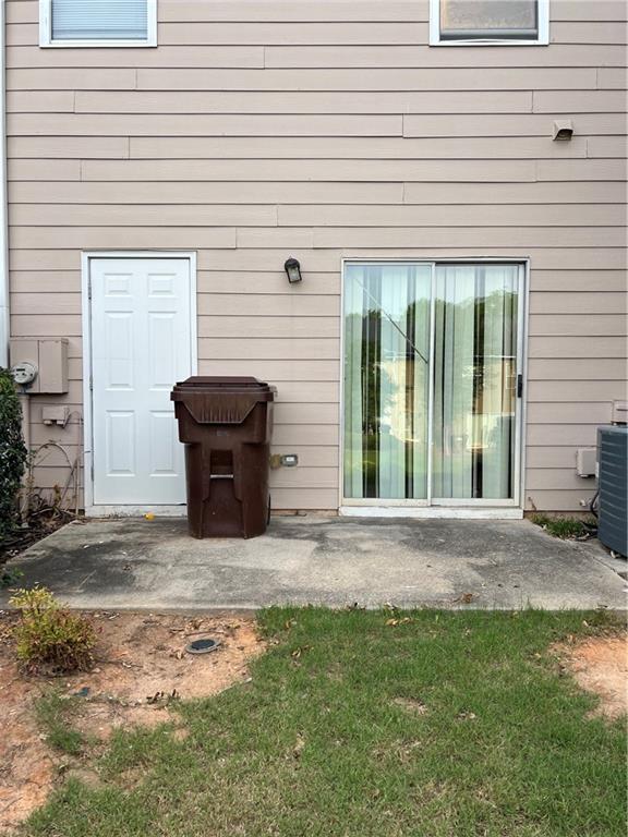 property entrance featuring a patio, central AC unit, and a lawn