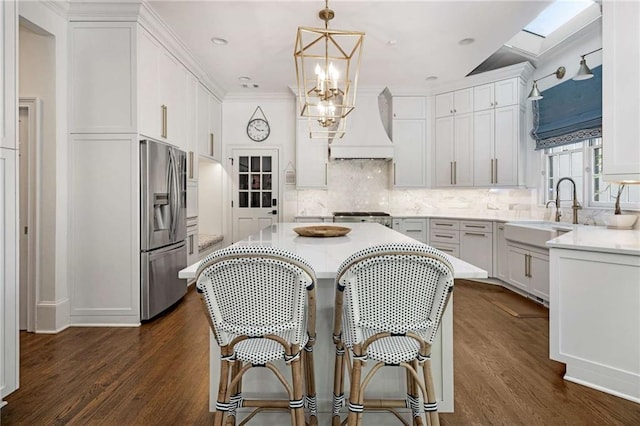 kitchen with dark hardwood / wood-style floors, pendant lighting, white cabinetry, sink, and stainless steel fridge