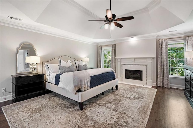 bedroom featuring crown molding, ceiling fan, dark hardwood / wood-style floors, and a raised ceiling