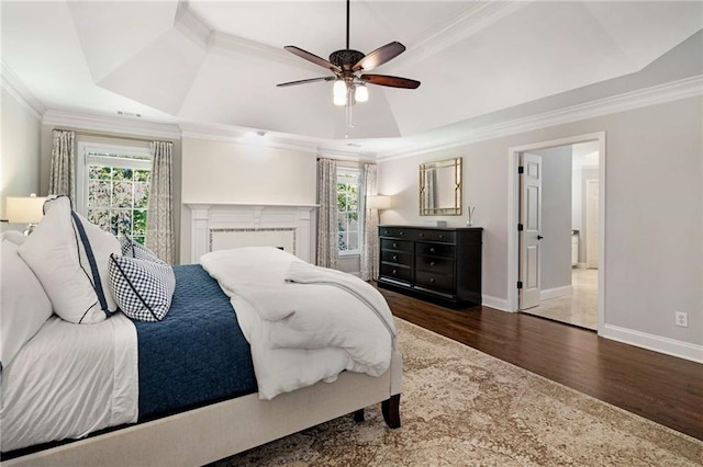 bedroom featuring dark hardwood / wood-style flooring, ornamental molding, ceiling fan, and a tray ceiling