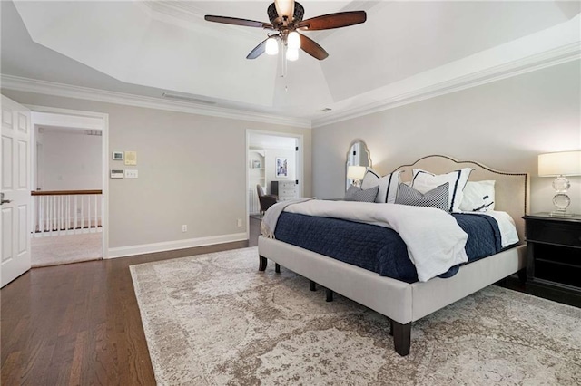 bedroom with dark hardwood / wood-style floors, ceiling fan, ornamental molding, and a tray ceiling