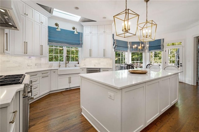 kitchen featuring pendant lighting, sink, white cabinetry, a center island, and high end stove