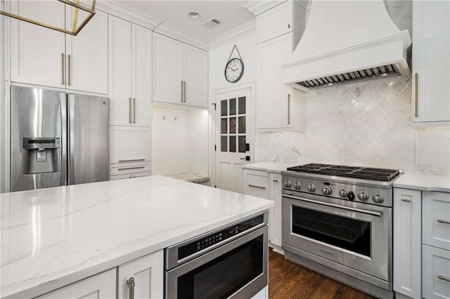 kitchen with appliances with stainless steel finishes, white cabinets, backsplash, custom exhaust hood, and light stone countertops