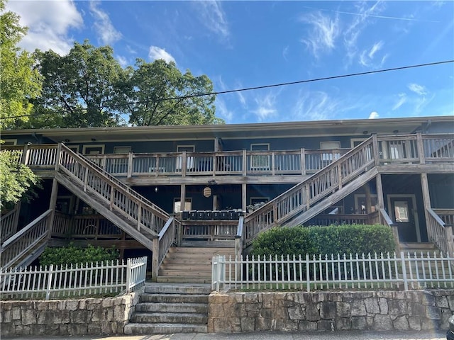 rear view of house with a deck, fence, and stairs