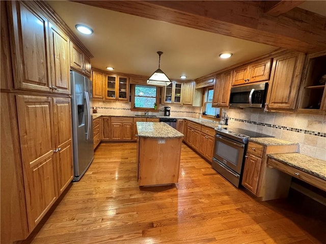 kitchen featuring pendant lighting, light wood-type flooring, a kitchen island, stainless steel appliances, and light stone countertops