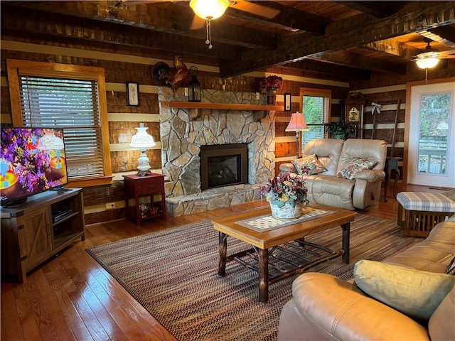 living room with wood-type flooring, wood walls, a fireplace, and a healthy amount of sunlight