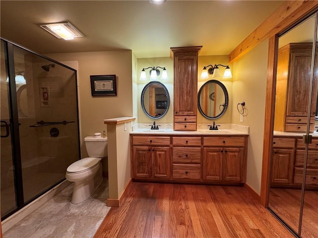 bathroom featuring hardwood / wood-style floors, vanity, toilet, and a shower with shower door