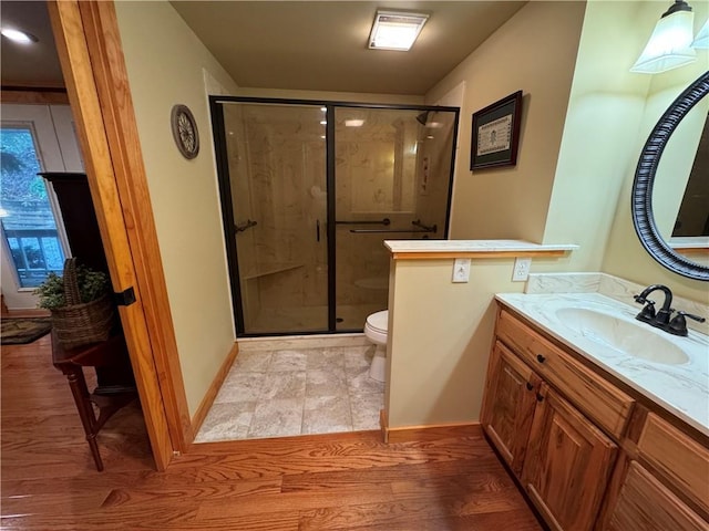 bathroom featuring wood-type flooring, walk in shower, vanity, and toilet