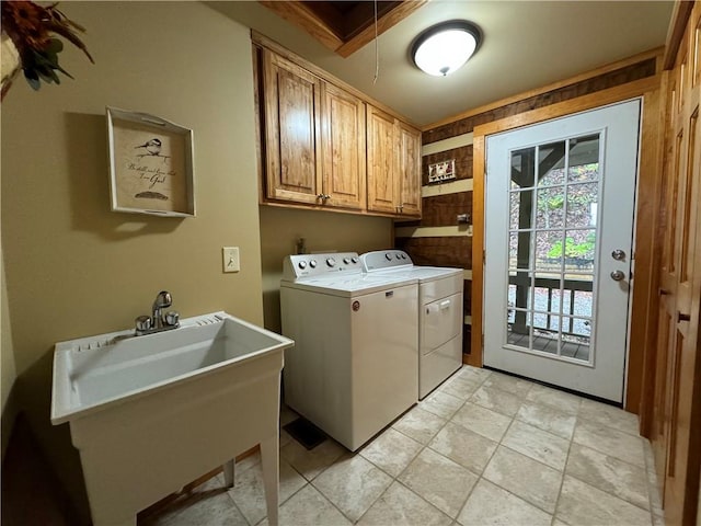 clothes washing area featuring washer and clothes dryer, cabinets, crown molding, and sink