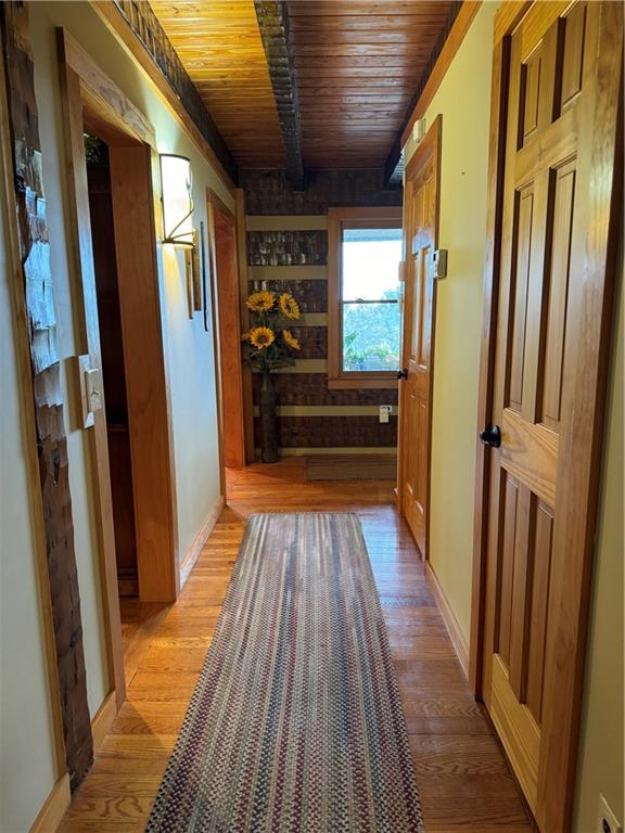 hallway with light hardwood / wood-style flooring and wooden ceiling