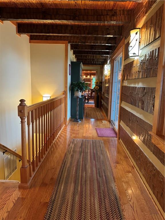 hall with wood-type flooring, wood ceiling, and beam ceiling