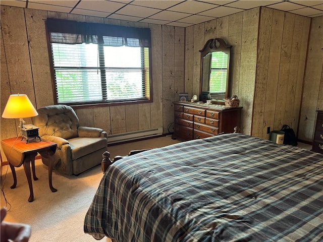 carpeted bedroom featuring a baseboard radiator, a paneled ceiling, and wood walls