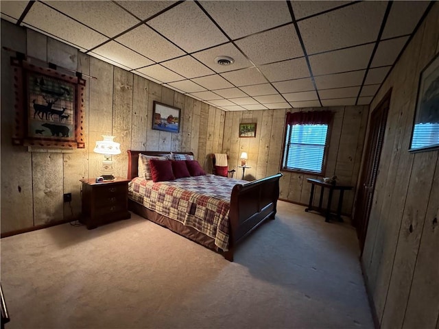 bedroom with a drop ceiling and wood walls