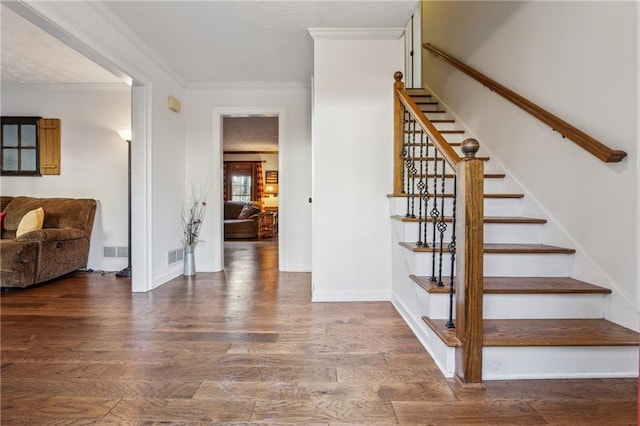 stairway featuring wood finished floors, visible vents, and ornamental molding