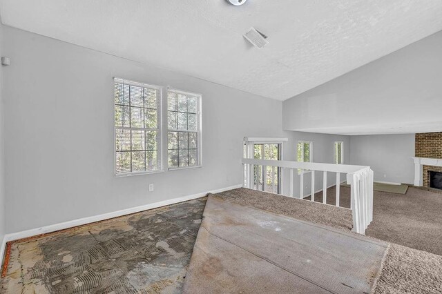 5338 Timor Trl, Lithonia, GA 30038 - carpeted spare room featuring a brick fireplace, lofted ceiling, baseboards, a textured ceiling, and stairs