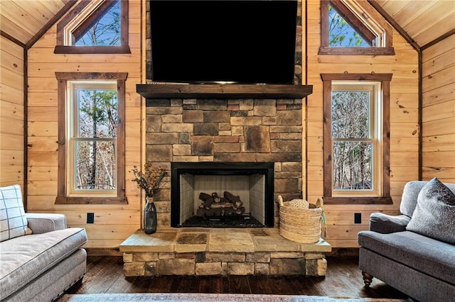 living area featuring lofted ceiling, wood-type flooring, wooden walls, and a fireplace