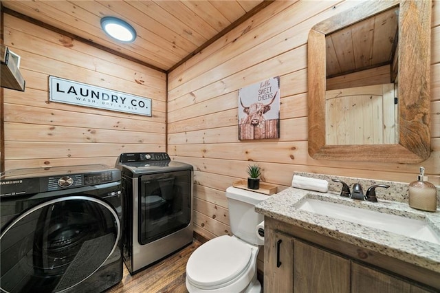 bathroom with wooden ceiling, toilet, wooden walls, vanity, and washing machine and clothes dryer