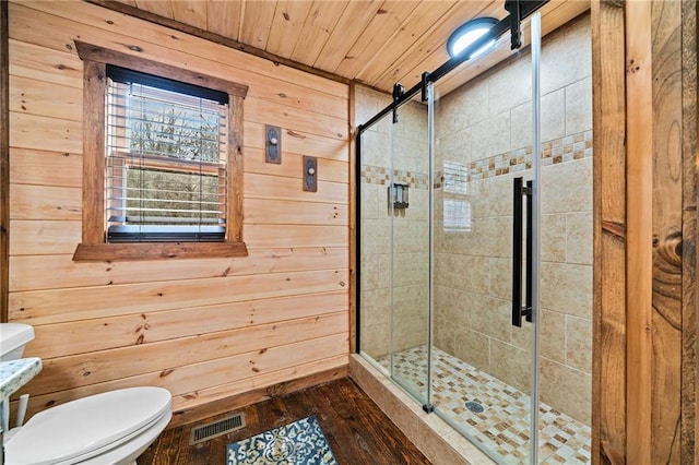 bathroom featuring toilet, wood walls, a shower stall, and visible vents