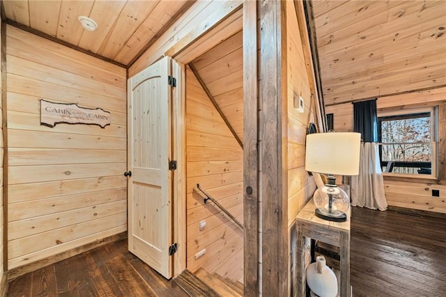 corridor with vaulted ceiling, dark wood-style flooring, wood walls, and wooden ceiling