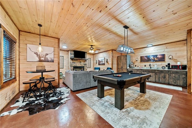 playroom featuring wood ceiling, a sink, a stone fireplace, concrete flooring, and billiards