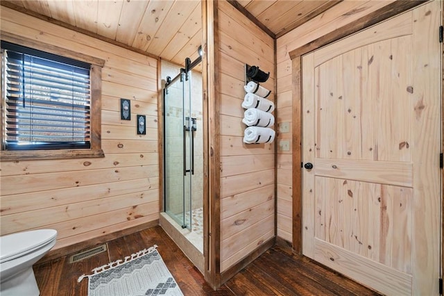 bathroom featuring toilet, wood walls, a shower stall, and visible vents