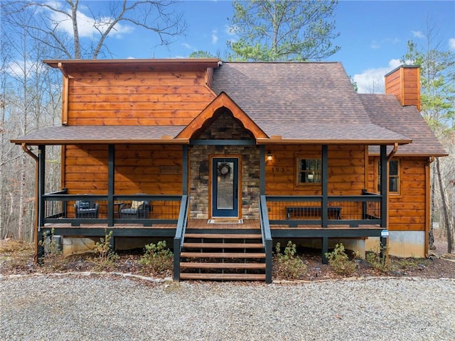 view of front of property featuring a shingled roof, covered porch, and a chimney