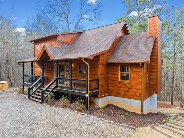 rustic home with covered porch, roof with shingles, and a chimney