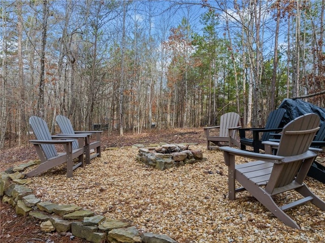 view of yard with a fire pit and a wooded view