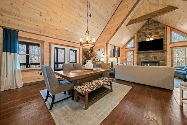 dining space featuring high vaulted ceiling, wood walls, a fireplace, french doors, and dark wood finished floors