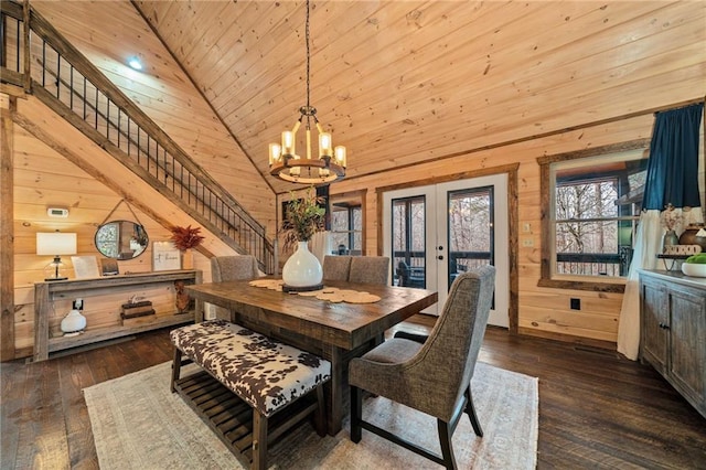 dining room with stairway, a notable chandelier, wooden walls, and hardwood / wood-style flooring