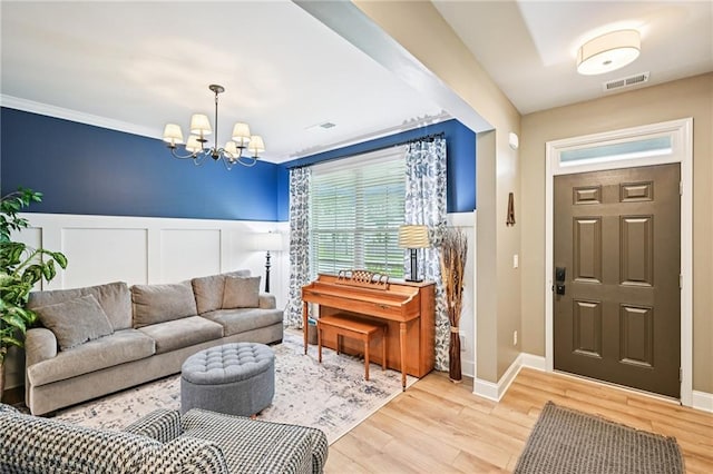 215 Dragonfly Way, Winder, GA 30680 - living area featuring a chandelier, a wainscoted wall, light wood-style floors, a decorative wall, and crown molding