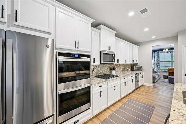 215 Dragonfly Way, Winder, GA 30680 - kitchen featuring appliances with stainless steel finishes, light wood-style floors, white cabinetry, recessed lighting, and tasteful backsplash