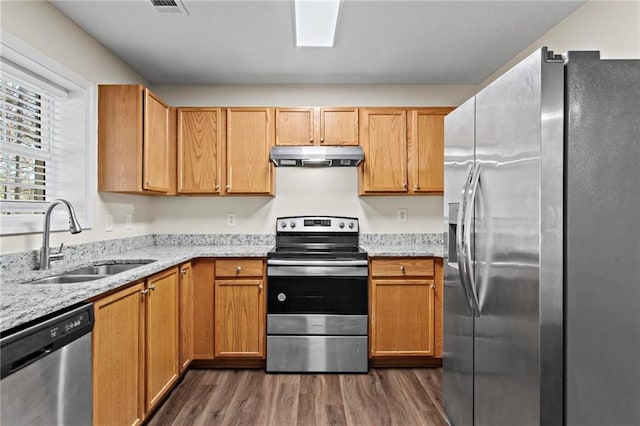 kitchen featuring sink, dark wood-type flooring, light stone countertops, and appliances with stainless steel finishes