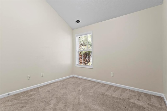 carpeted empty room featuring vaulted ceiling