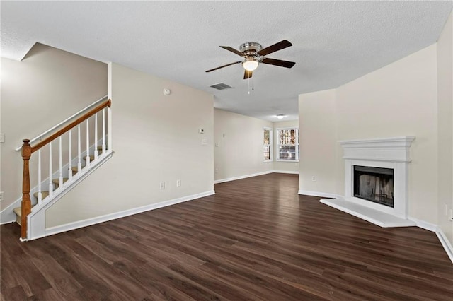 unfurnished living room with ceiling fan, dark wood-type flooring, and a textured ceiling