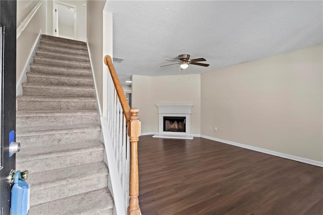 stairs with hardwood / wood-style floors and ceiling fan