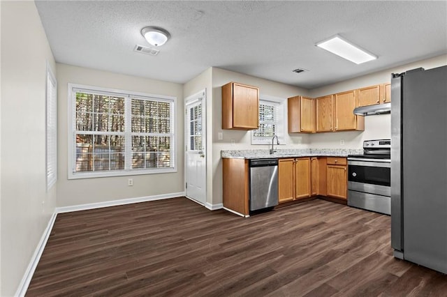 kitchen featuring appliances with stainless steel finishes, sink, dark wood-type flooring, and a textured ceiling