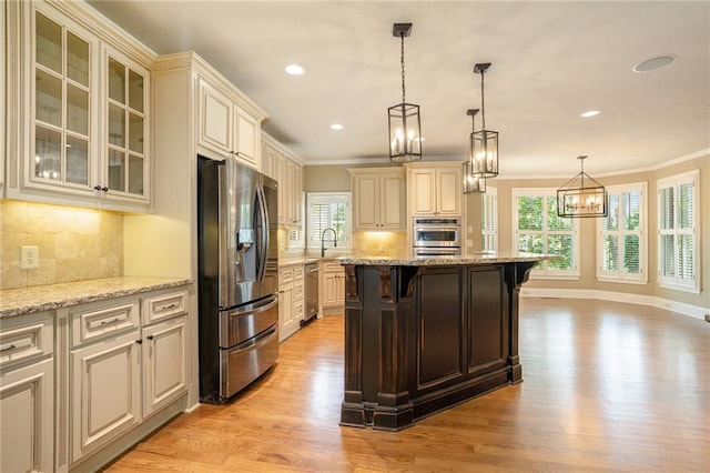 kitchen with a breakfast bar, a sink, appliances with stainless steel finishes, cream cabinetry, and crown molding