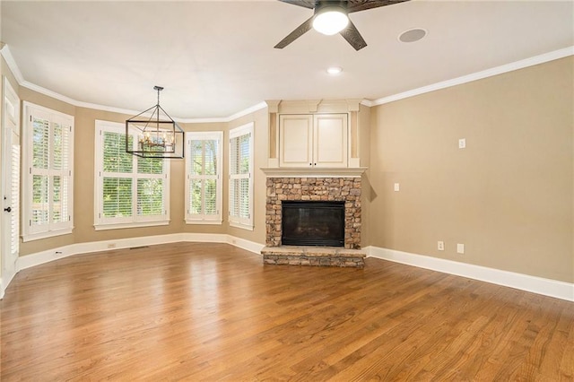 unfurnished living room with baseboards, ornamental molding, light wood-type flooring, a fireplace, and ceiling fan with notable chandelier