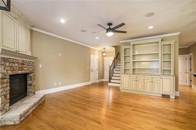 unfurnished living room with a fireplace, stairway, light wood-style floors, a ceiling fan, and baseboards