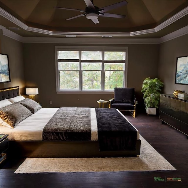 bedroom with ceiling fan, a tray ceiling, hardwood / wood-style flooring, and crown molding