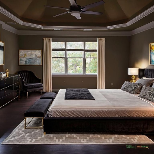 bedroom with ornamental molding, a tray ceiling, a ceiling fan, and wood finished floors